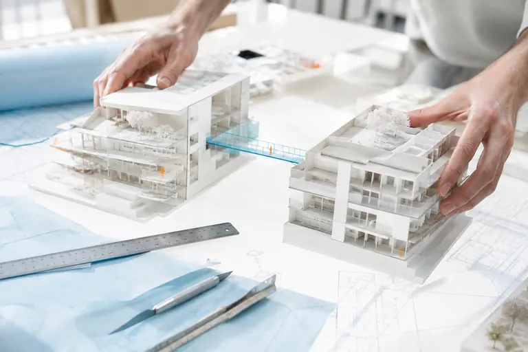 Deux maquettes d’architecture blanches assemblées sur une table lumineuse, image d’une fusion de sites