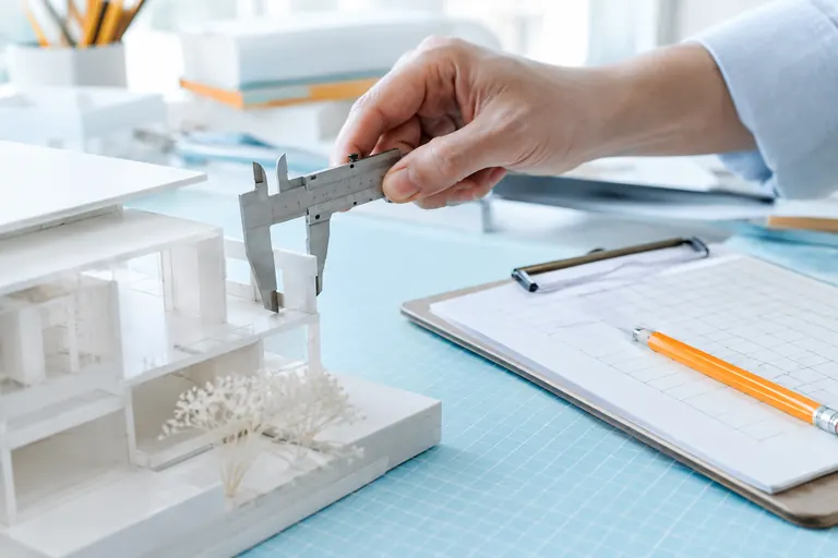 Main mesurant une maquette blanche au pied à coulisse pendant une recette SEO